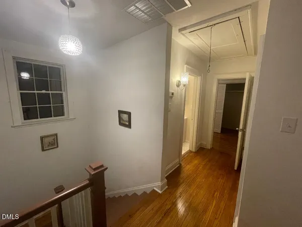 a view of a hallway with wooden floor and a bathroom
