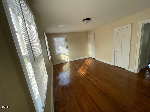 a view of an empty room with wooden floor and stairs