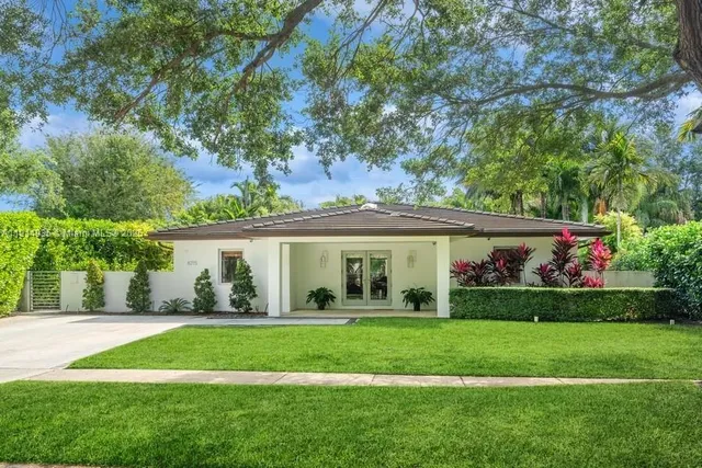 a view of house with a big yard and potted plants and large trees