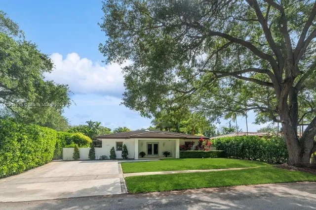 a view of a big house with a big yard and large trees