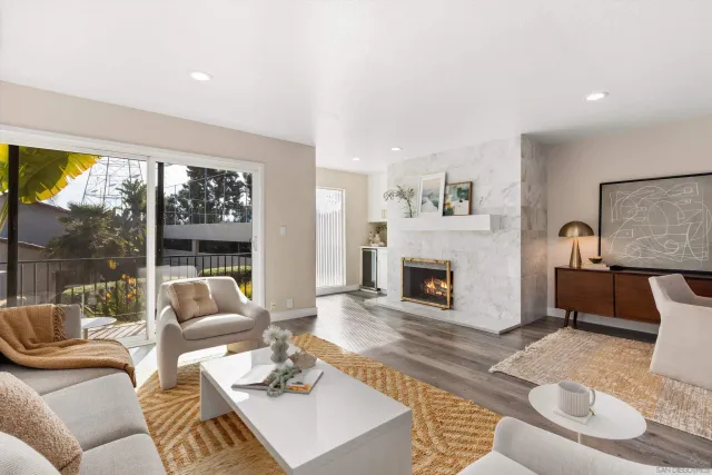 a living room with furniture a fireplace and a large window with balcony view