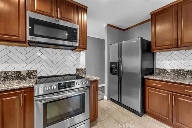 a kitchen with granite countertop wooden cabinets and stainless steel appliances