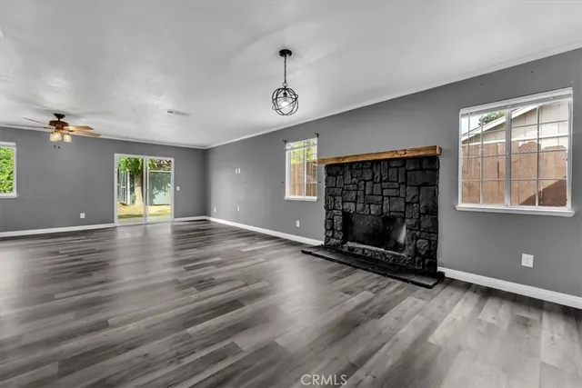 an empty room with wooden floor cabinet and windows