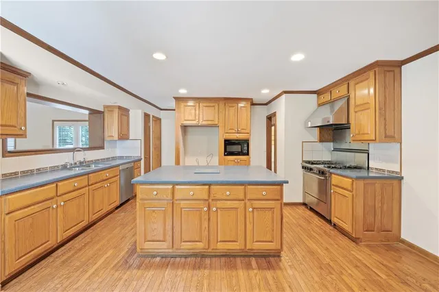 a large kitchen with stainless steel appliances granite countertop a stove a sink dishwasher and a microwave oven with wooden floor