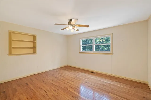 a view of a room with wooden floor and a ceiling fan