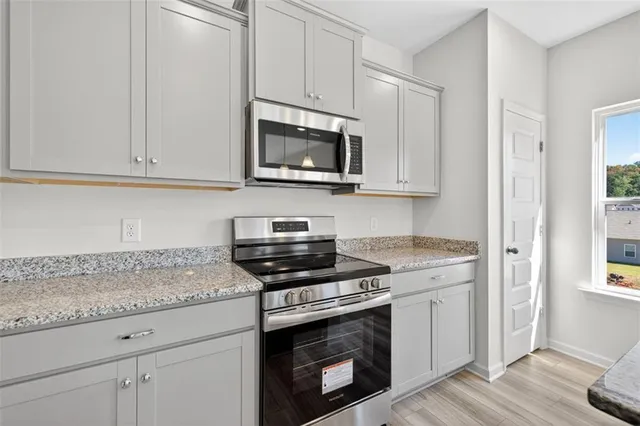 a kitchen with granite countertop a stove top oven microwave and cabinets