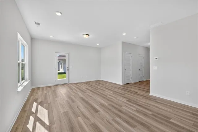 a view of an empty room with window and wooden floor