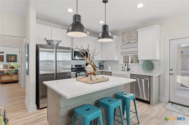 a kitchen with stainless steel appliances a stove a sink a refrigerator a table and chairs