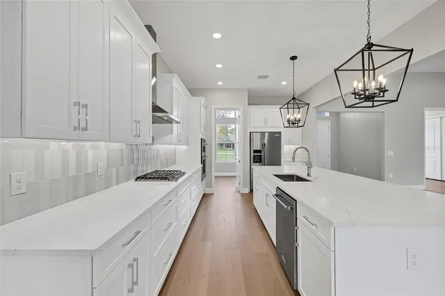 a large white kitchen with a sink dishwasher a fireplace with a dining table and chairs