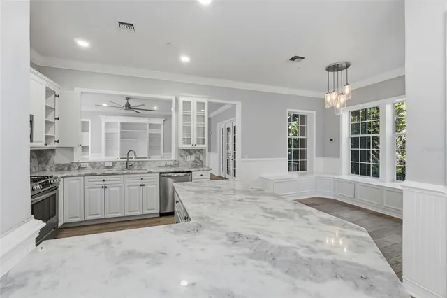 a large kitchen with kitchen island a stove a sink dishwasher a refrigerator and white cabinets with wooden floor