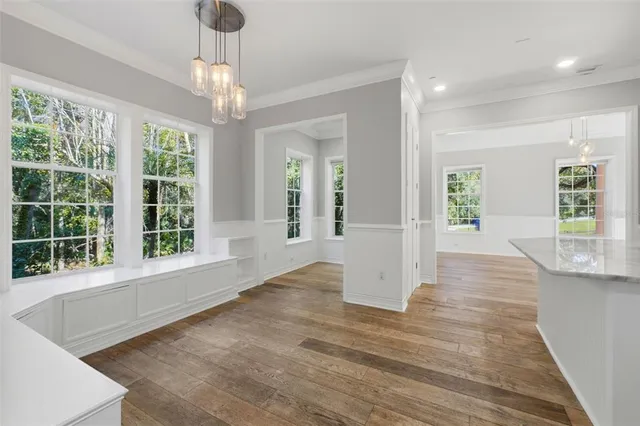 a large kitchen with stainless steel appliances granite countertop a large center island a stove a refrigerator white cabinets and wooden floor