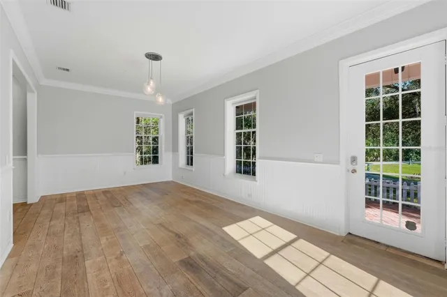 a large white kitchen with granite countertop a stove a sink a refrigerator and white cabinets with wooden floor