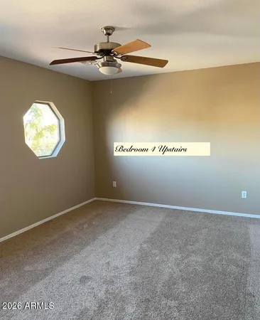an empty room with windows and chandelier fan