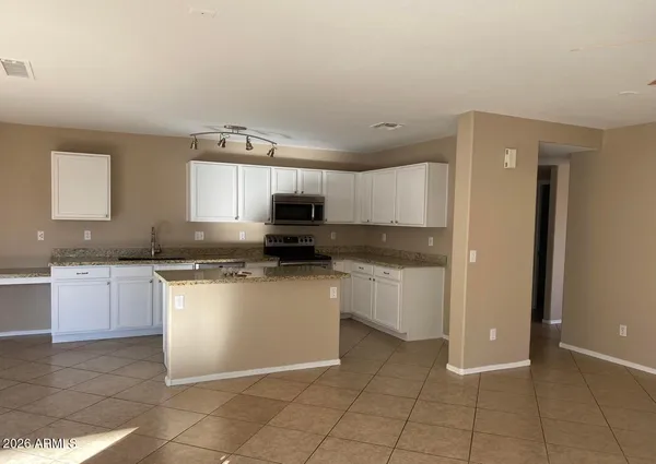 a kitchen with a sink a stove top oven and white cabinets