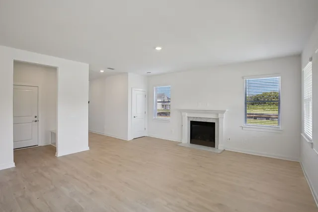 an empty room with windows and fireplace