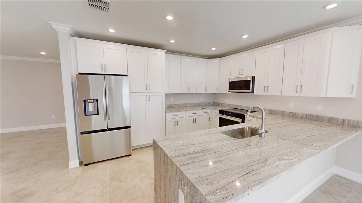 418 Easy Street Sebastian, FL 32958 - Photo 8 of 34 a kitchen with white cabinets and stainless steel appliances