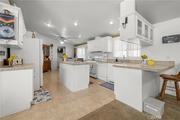 a kitchen with stainless steel appliances granite countertop a refrigerator sink and white cabinets