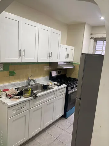 a kitchen with stainless steel appliances granite countertop a stove a refrigerator and a white cabinets