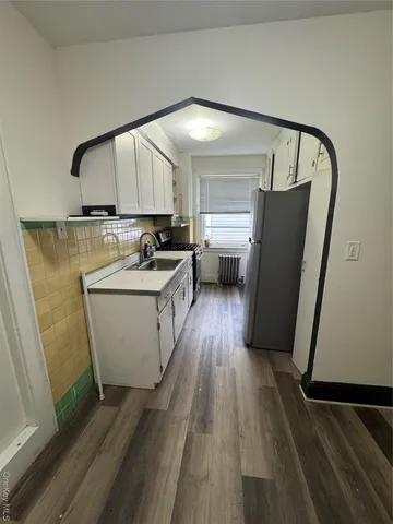 a kitchen with a sink a refrigerator and wooden floor