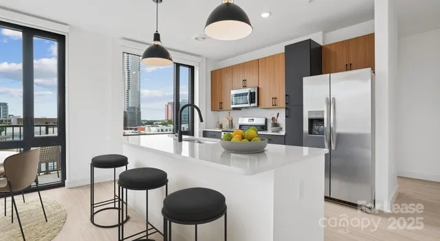 a kitchen with stainless steel appliances granite countertop a table chairs and a refrigerator