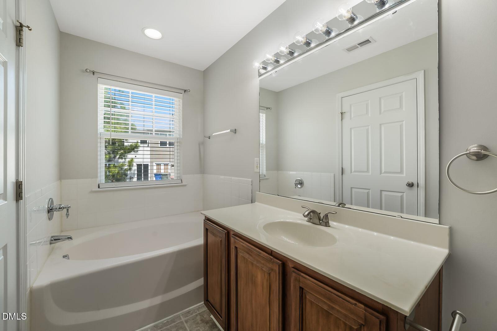 4909 Blue Rock Court Raleigh, NC 27610 - Photo 13 of 15 a bathroom with a sink double vanity granite tub and a mirror