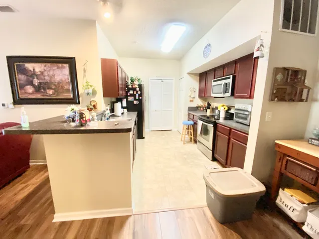 a living room with stainless steel appliances furniture a flat screen tv and a refrigerator