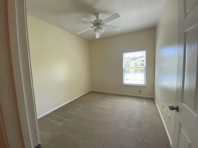 an empty room with a window and a fan