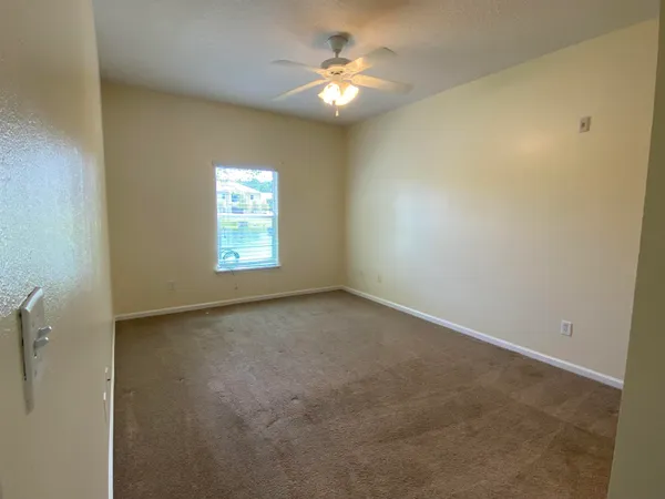 an empty room with windows and a ceiling fan