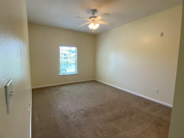 an empty room with windows and a ceiling fan