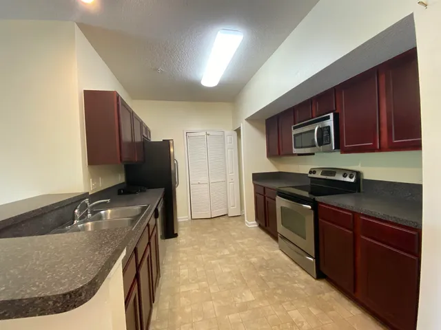 a kitchen with granite countertop a sink stove and refrigerator