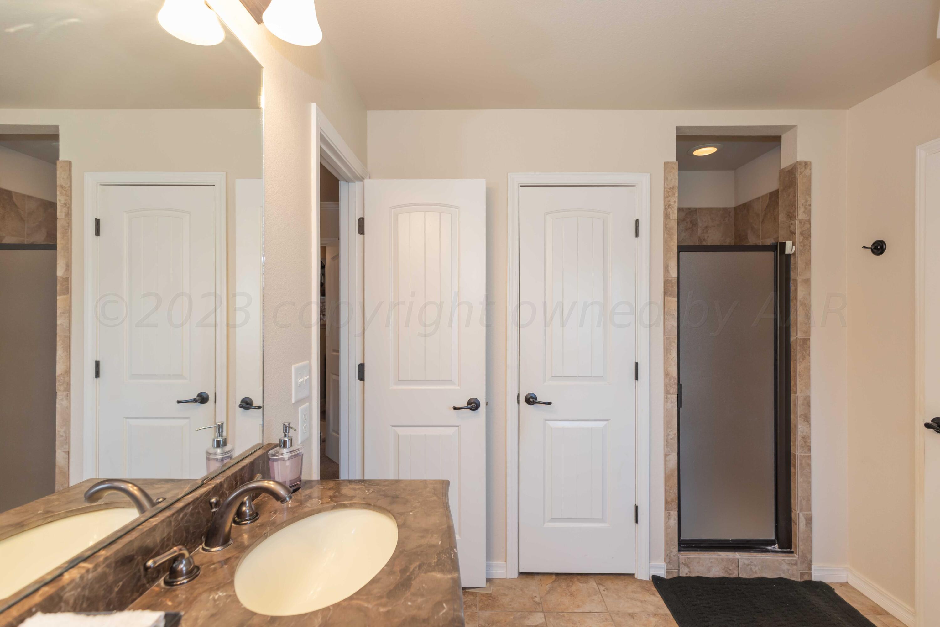 5904 South Rusk Street Amarillo, TX 79118 - Photo 27 of 49 a bathroom with a granite countertop sink a mirror and a shower