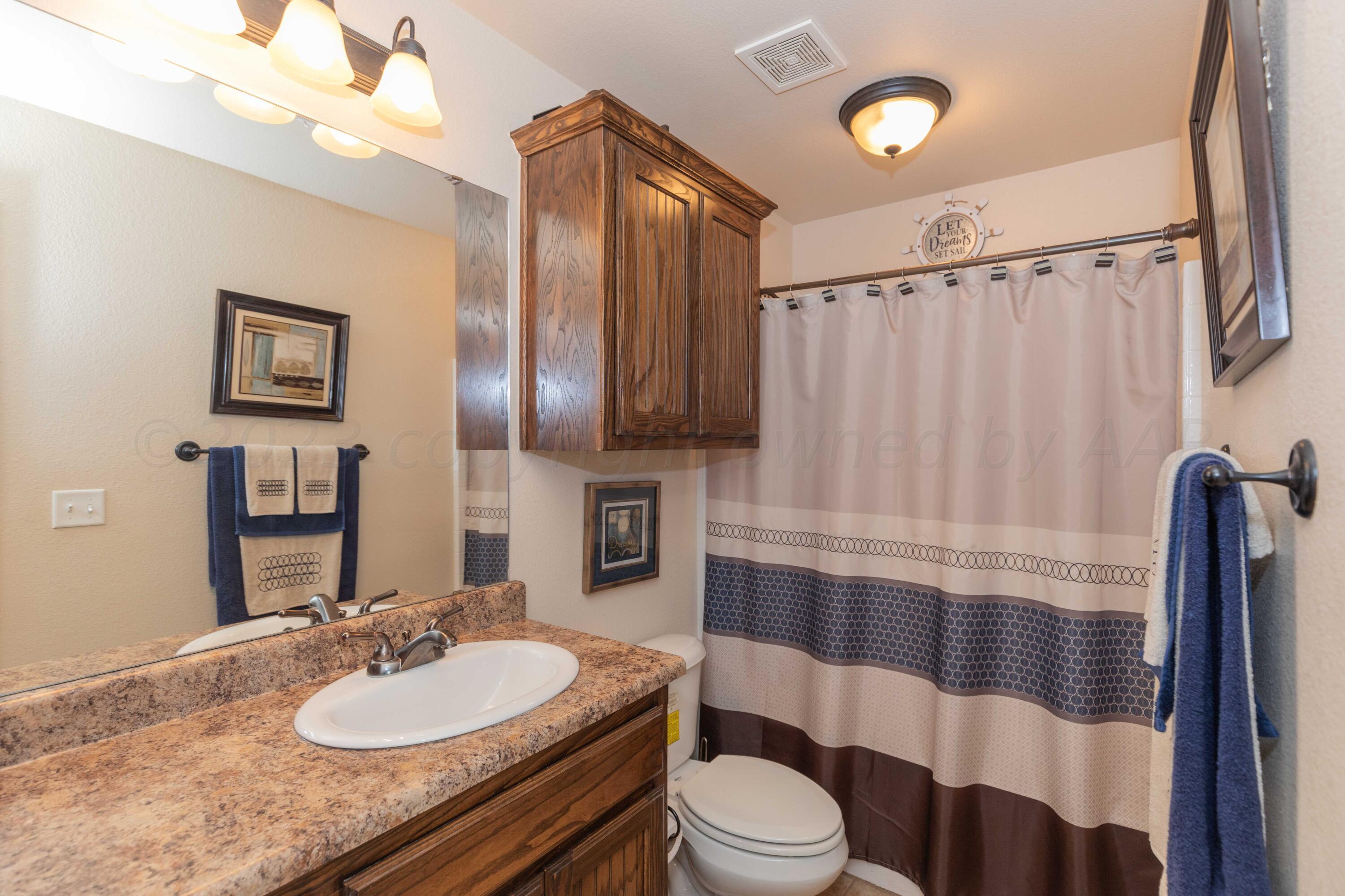 5904 South Rusk Street Amarillo, TX 79118 - Photo 33 of 49 a bathroom with a sink a toilet and shower curtain