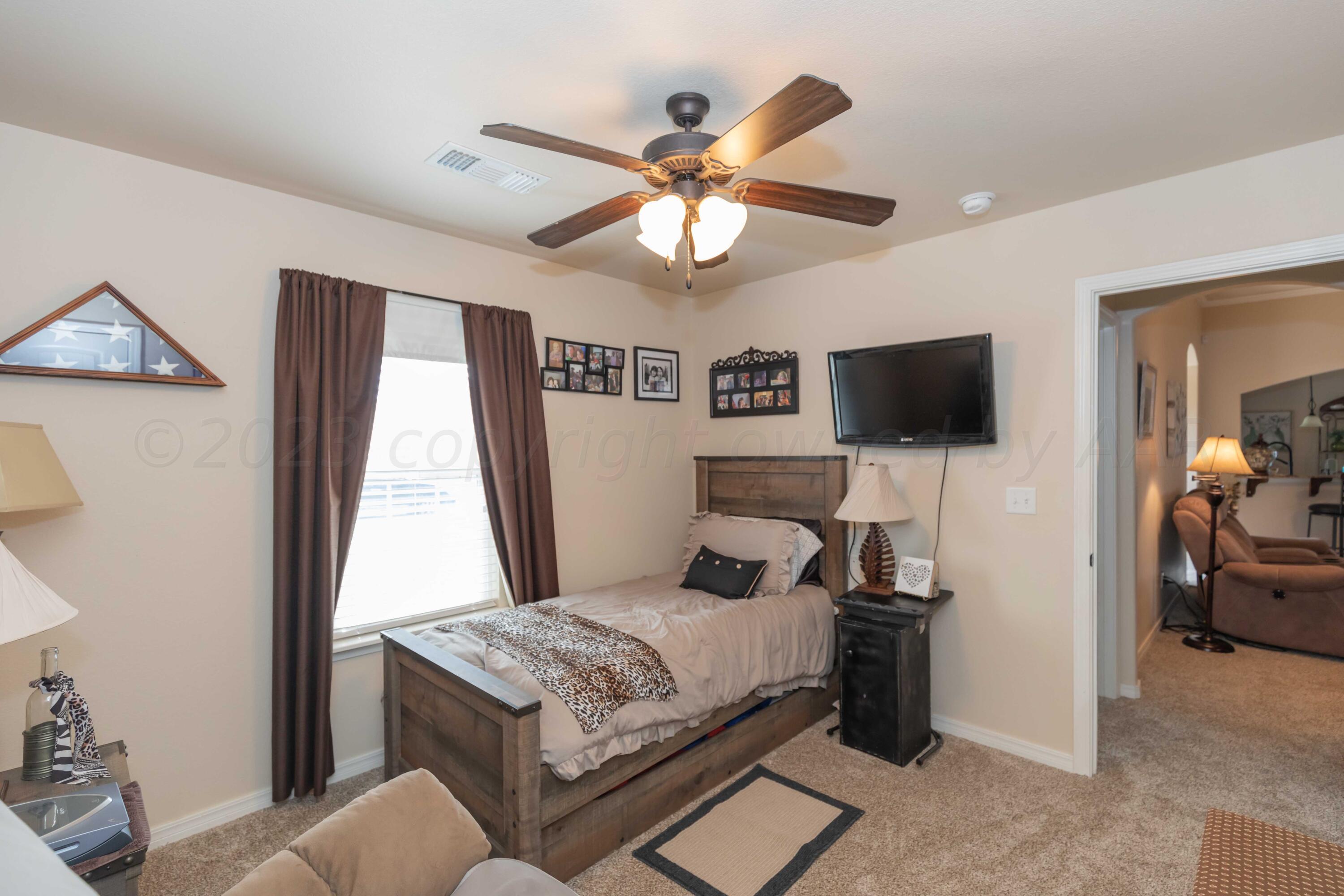 5904 South Rusk Street Amarillo, TX 79118 - Photo 36 of 49 a bedroom with a bed and a flat tv screen on dresser