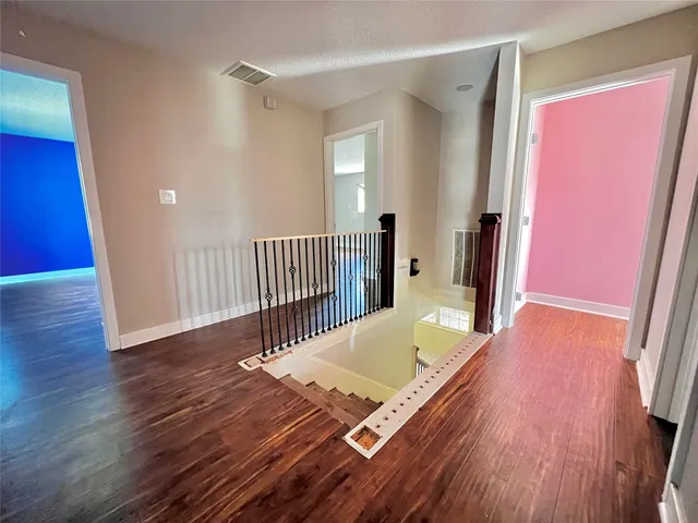 a view of a hallway with wooden floor and stairs