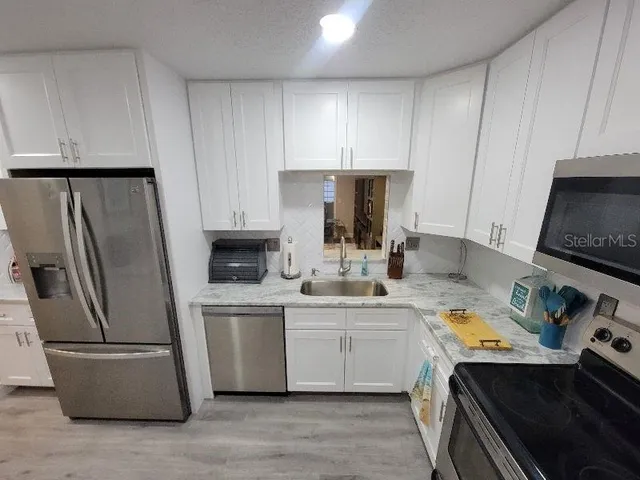 a kitchen with stainless steel appliances a stove a refrigerator a sink a stove and cabinets