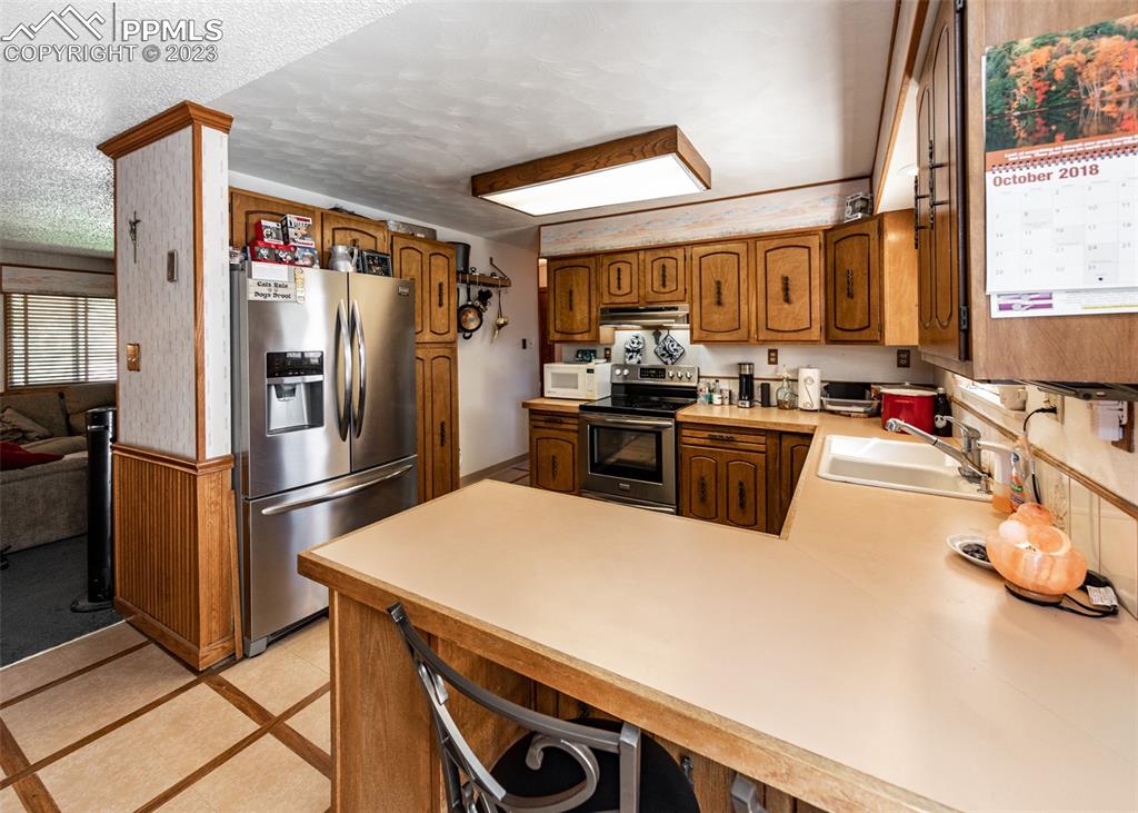 126 La Rochelle Drive Pueblo, CO 81005 - Photo 10 of 42 a kitchen with a sink a refrigerator and a stove top oven
