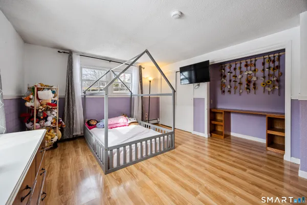 a bedroom with wooden floor a bed and a dresser