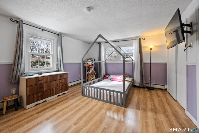 a bedroom with wooden floor a bed and a dresser