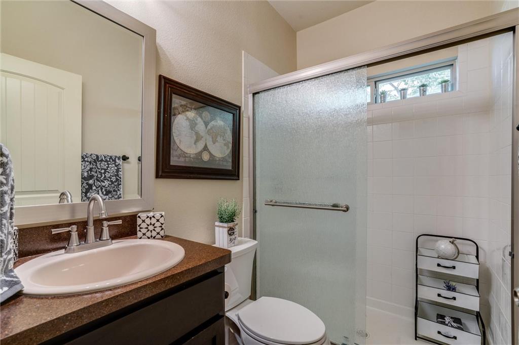 4606 Kind Way, Unit 285 Austin, TX 78725 - Photo 11 of 14 The bathroom features a vanity with a countertop and an oval sink, a toilet, and a shower with a frosted glass door