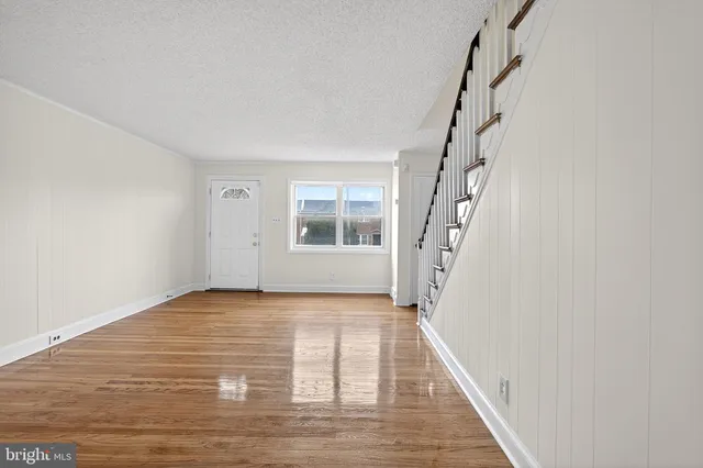 a view of an empty room with wooden floor and staircase