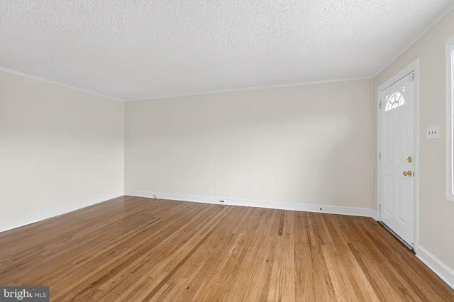 a view of room with wooden floor and white walls