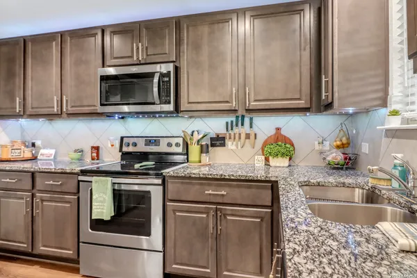 a kitchen with granite countertop a stove top oven microwave and cabinets