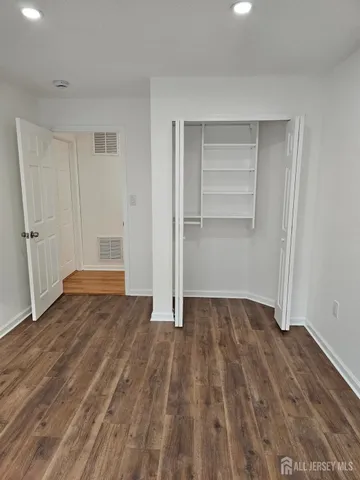 a view of an empty room with closet and wooden floor