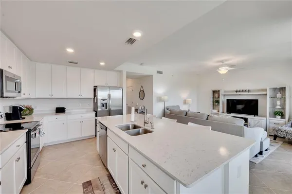 a kitchen with stainless steel appliances a refrigerator a stove a sink a dining table and chairs