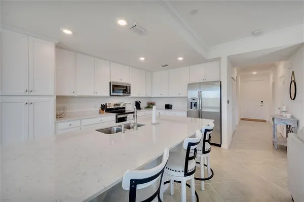 a kitchen with stainless steel appliances granite countertop a sink a stove a refrigerator cabinets and chairs