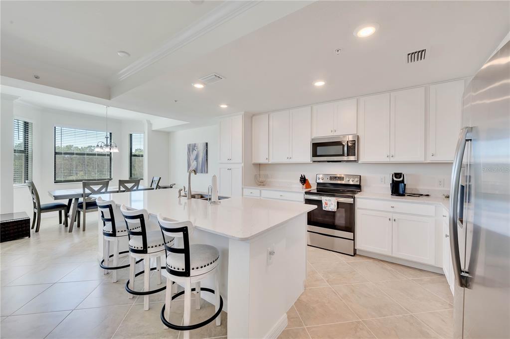 17510 Gawthrop Drive, Unit 203 Lakewood Ranch, FL 34211 - Photo 9 of 54 a kitchen with stainless steel appliances granite countertop a sink a stove a refrigerator cabinets and chairs