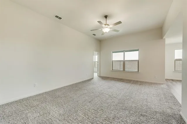 an empty room with windows and fan chandelier fan