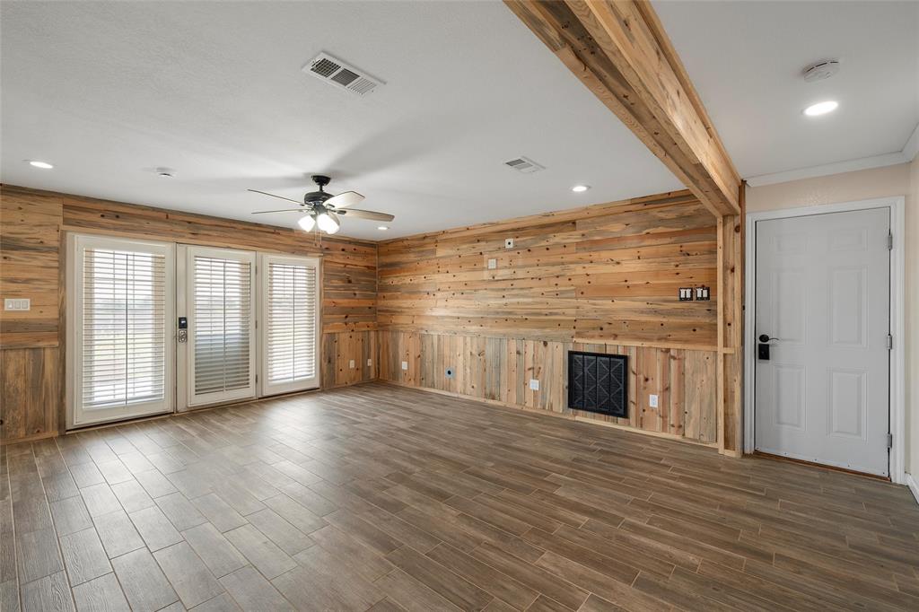 5112 Old Caufield Ranch Road McGregor, TX 76657 - Photo 17 of 38 Unfurnished living room with beamed ceiling, wood finished floors, wooden walls, ceiling fan, and recessed lighting