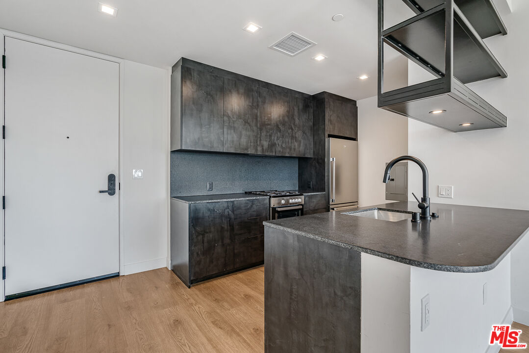 10700 Tabor Street, Unit 524 Los Angeles, CA 90034 - Photo 2 of 12 a kitchen with stainless steel appliances granite countertop a sink a stove and a refrigerator with wooden floor