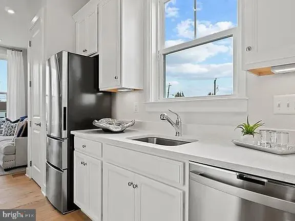a kitchen with stainless steel appliances white cabinets and a refrigerator
